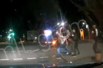 На оживленном перекрестке парня толкнули под колеса машины (видео)