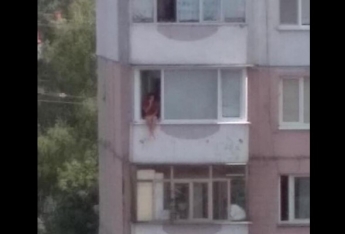 В Запорожье засняли девушку, сидящую на перекладине балкона