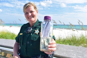 Патрулюючи пляж, поліцейська знайшла закриту пляшку із грошима та ще одним дивним вмістом (фото)