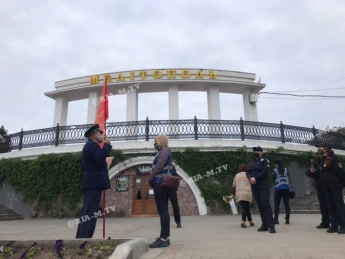 Дюжина полицейских в Мелитополе пытается убедить пенсионера с красным флагом уйти с Аллеи Славы (фото, видео)