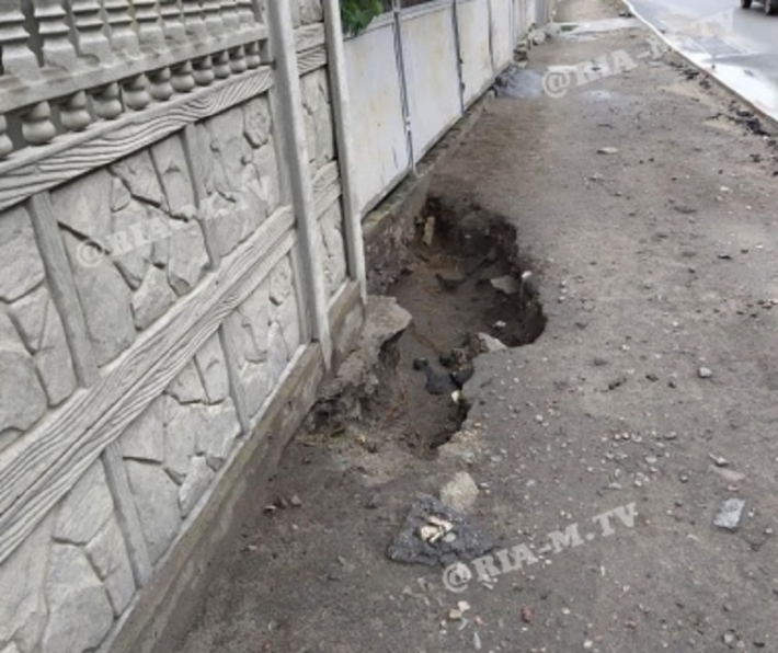 В Мелитополе на тротуаре появилась огромная яма - вода заливает двор (фото)