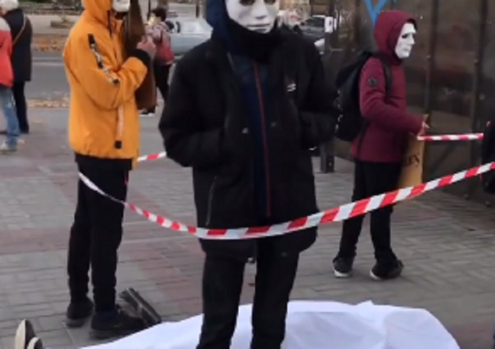 В Мелитополе возле остановки люди в масках и с табличками окружили "труп" (видео)