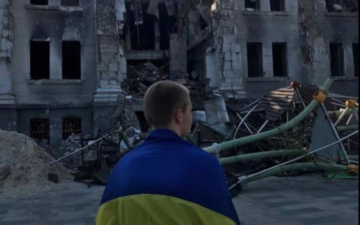 В Мариуполе парень вышел на площадь возле разбомбленного Драмтеатра с флагом Украины (фото)